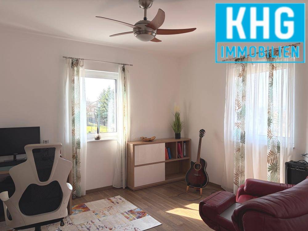 Helles Arbeitszimmer mit Schreibtisch, Regal und Deckenventilator.