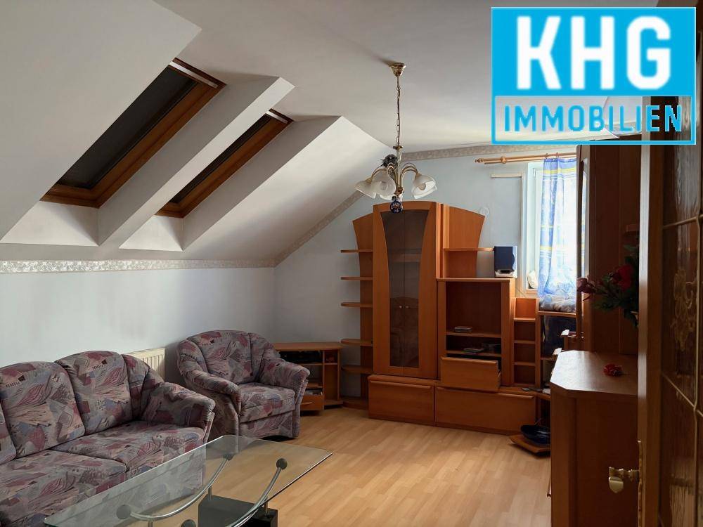 Wohnzimmer im Dachgeschoss mit Schrägen, Dachfenstern und gemütlicher Einrichtung.