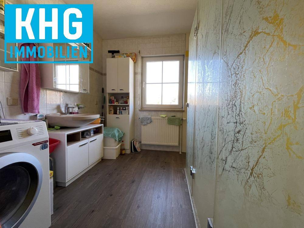 Helles Badezimmer mit Waschbecken, Spiegelschrank und Fenster, inklusive Waschmaschine.