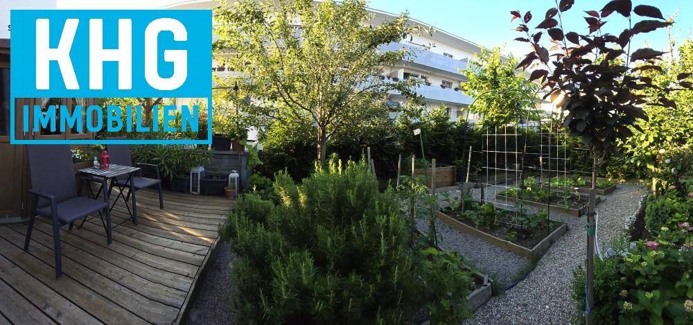 Weitläufiger Garten mit Hochbeeten, Holzterrasse und üppiger Bepflanzung.