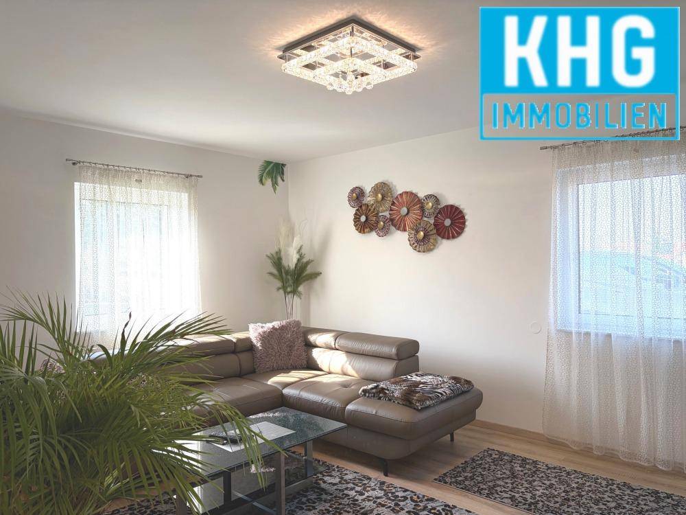 Gemütliches Wohnzimmer mit Ecksofa, Couchtisch und großen Fenstern.