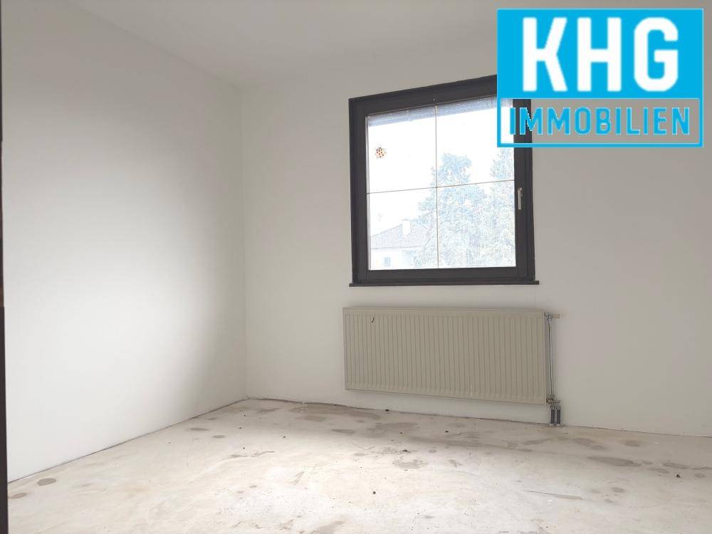 Leeres Zimmer mit Fenster und Heizkörper, ideal als Schlaf- oder Arbeitszimmer.