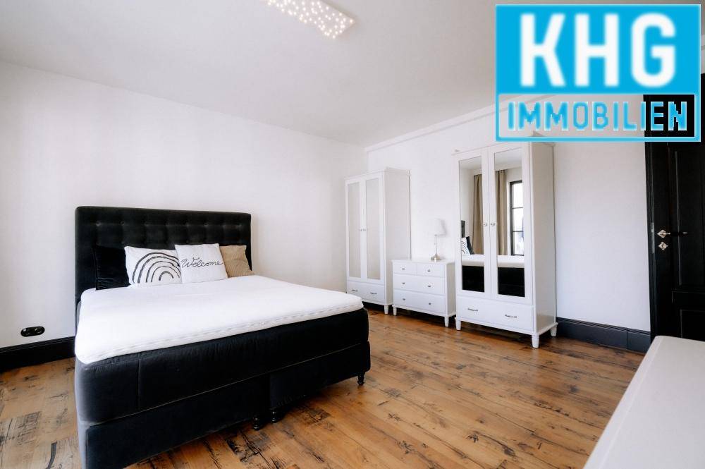 Helles Schlafzimmer mit schwarzem Bett, weißen Kleiderschränken und rustikalem Holzboden.