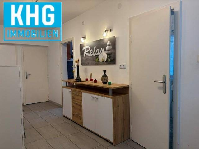 Heller Flur mit Fliesenboden, modernem Sideboard und mehreren Türen.