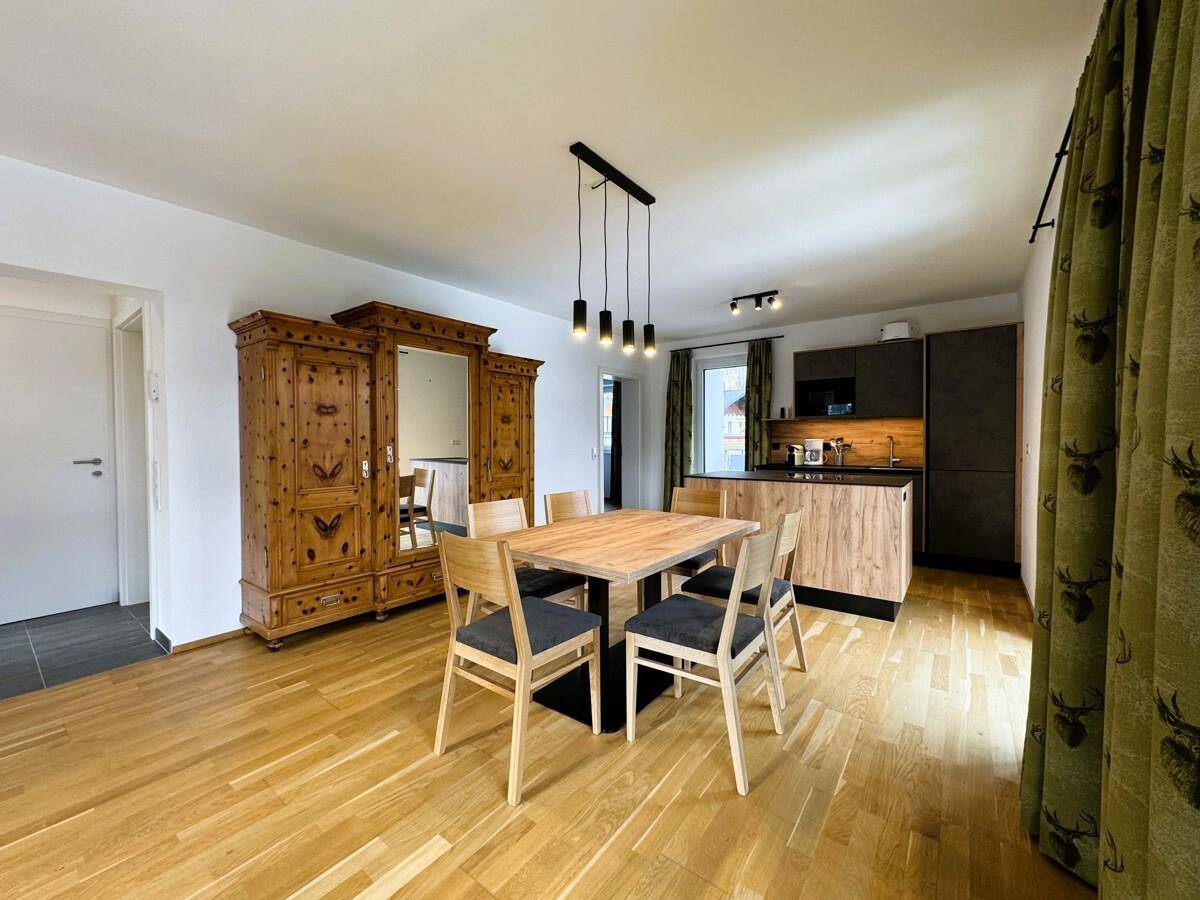 Geräumiger Wohn-Essbereich mit Holzboden, Esstisch und integrierter moderner Küche.