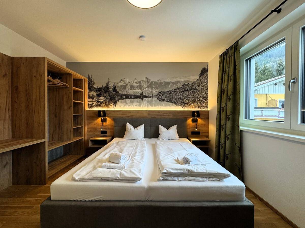 Modernes Schlafzimmer mit Doppelbett, Holzelementen und indirekter Beleuchtung.