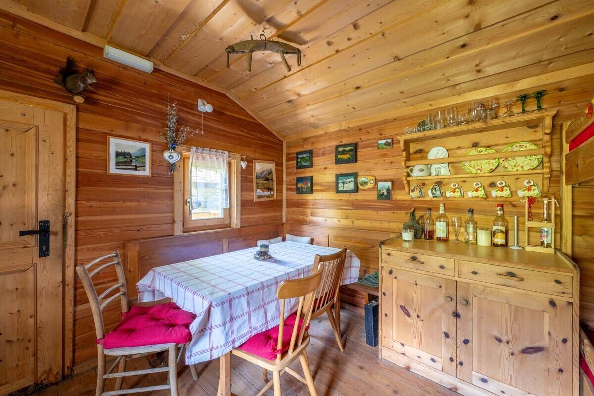 Rustikaler Essbereich in einer Holzhütte mit Holztisch, Stühlen und traditionellem Schrank.