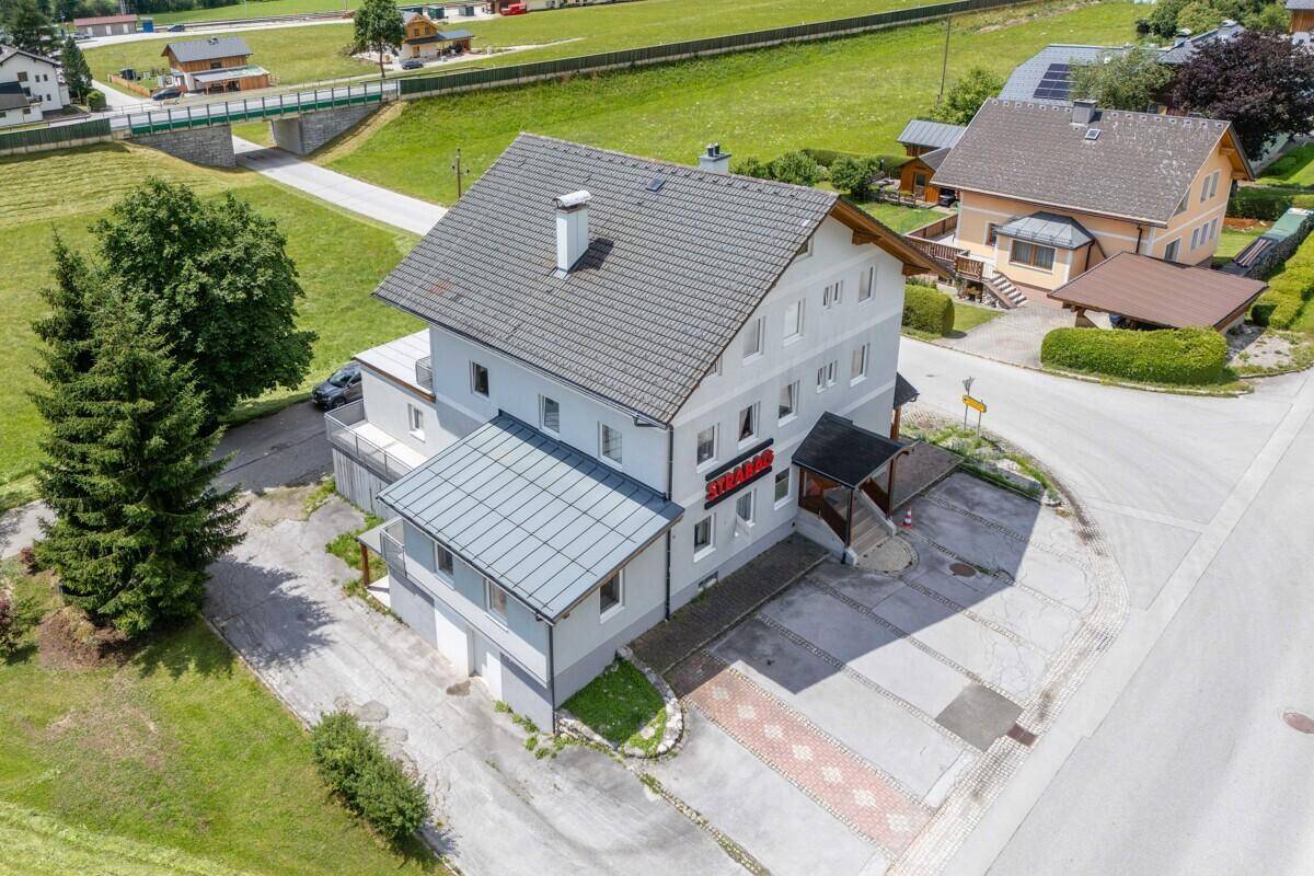 Gebäudeansicht von oben mit Parkplätzen und der umliegenden Naturlandschaft.