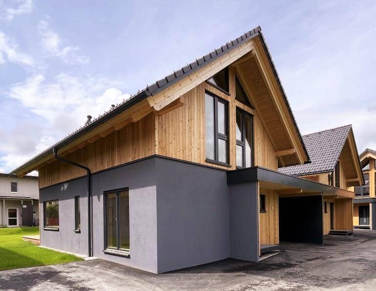 Moderne Hausfassade mit dunklem Putz und Holzverkleidung, ergänzt durch einen praktischen Carport.