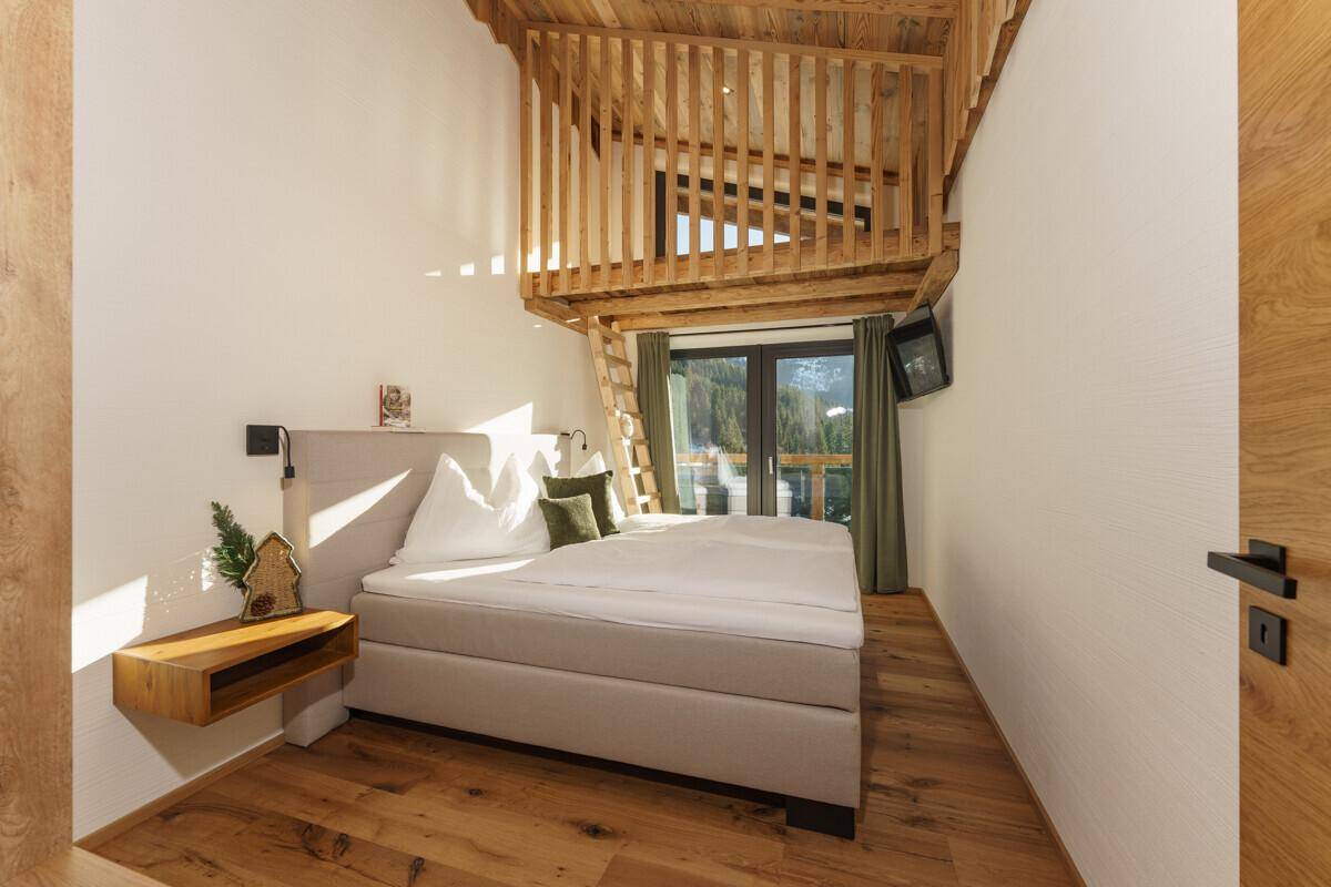 Schlafzimmer mit Doppelbett, Holzboden und einer charmanten Holzgalerie unter der Decke.