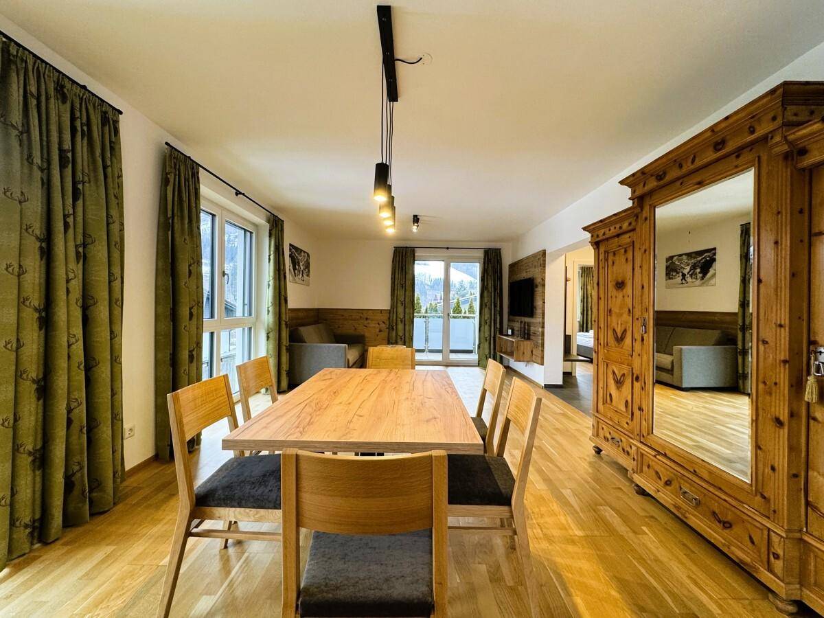 Heller Wohn-Essbereich mit Holzboden, großem Esstisch und traditionellem Holzschrank.