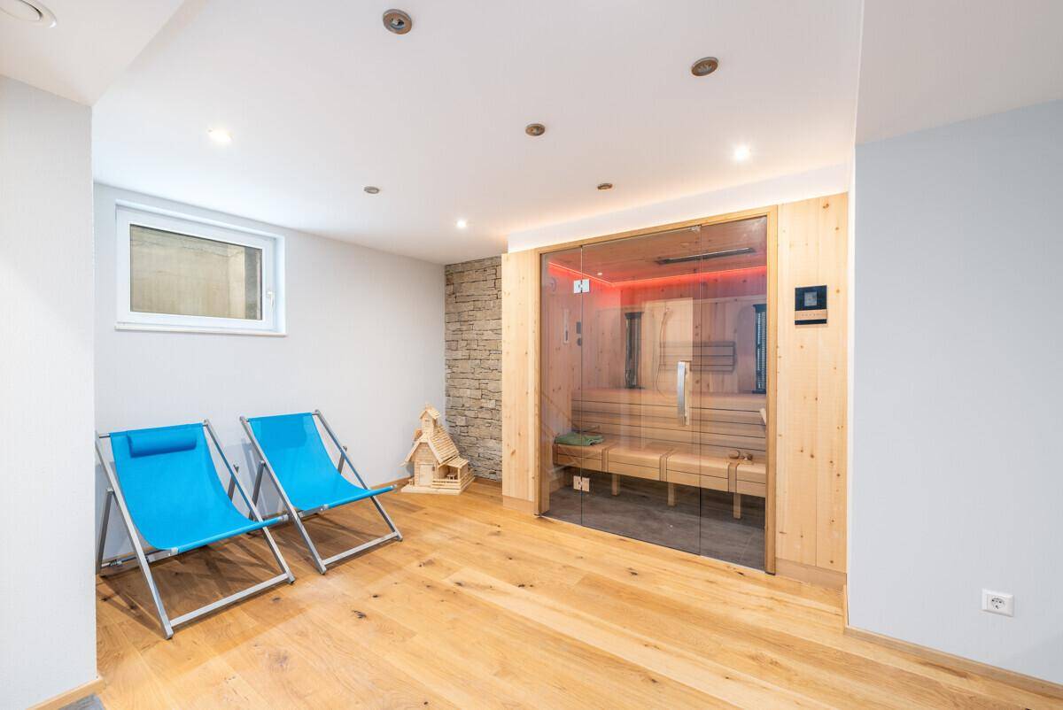 Moderner Wellnessbereich mit Sauna, Liegestühlen und indirekter Beleuchtung für Entspannung.