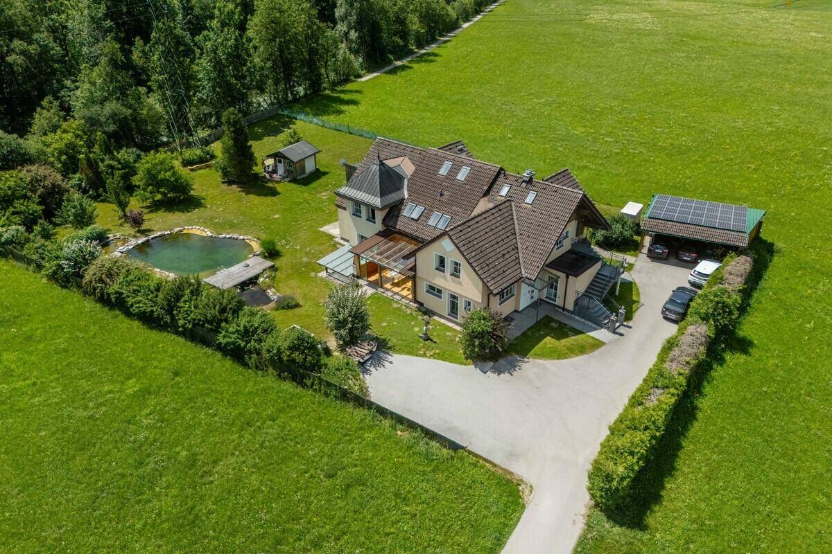 Luftaufnahme eines Anwesens mit großem Garten, Teich und Photovoltaikanlage.