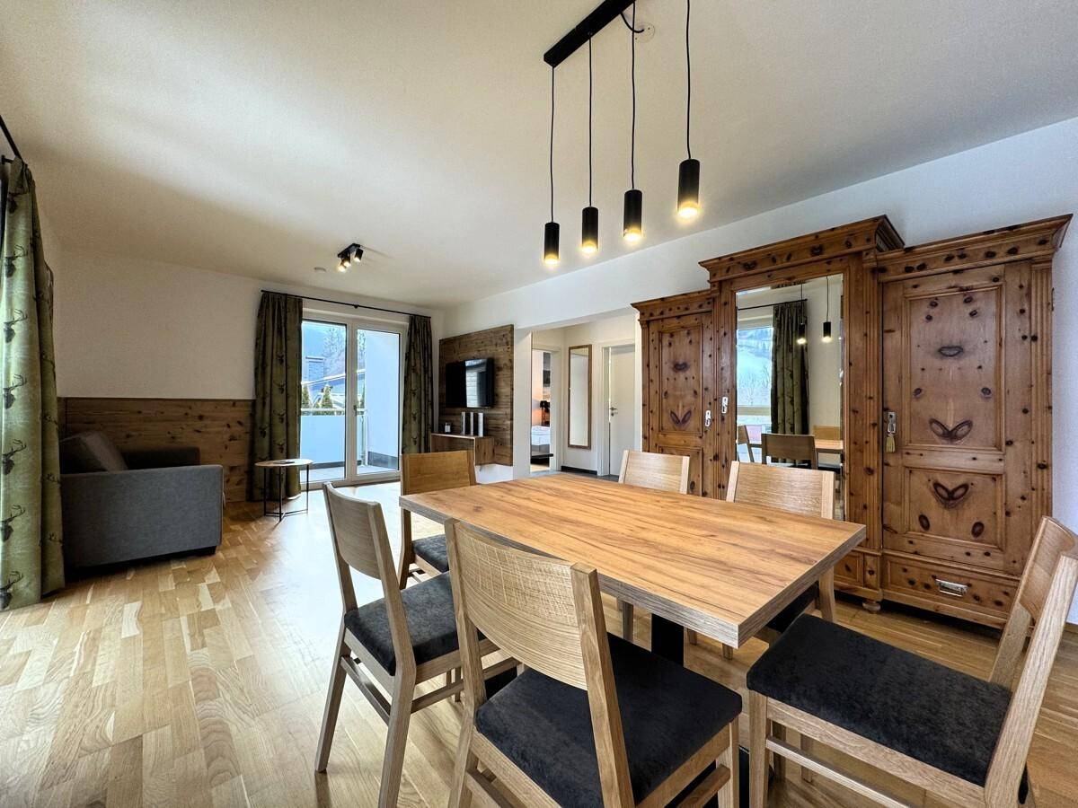 Geräumiger Wohn-Essbereich mit Holzboden, Esstisch und traditionellem Holzschrank.