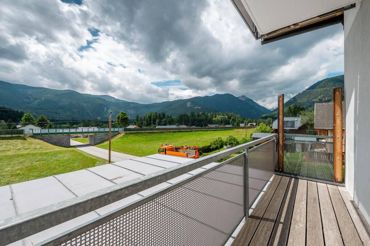 Balkon mit Holzboden und Panoramablick auf die grüne Landschaft und die Berge.