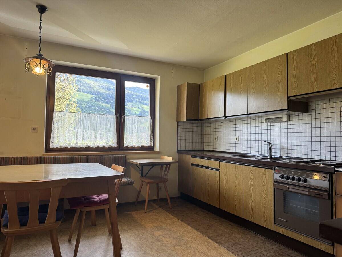 Geräumige Wohnküche mit Esstisch, Holzmöbeln und einem Fenster mit Bergblick.