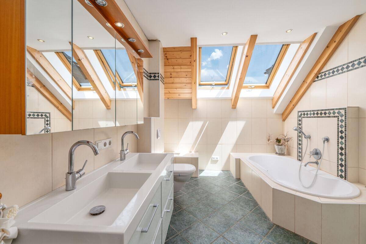 Geräumiges Badezimmer mit Doppelwaschbecken, Badewanne und Dachfenstern für viel Tageslicht.