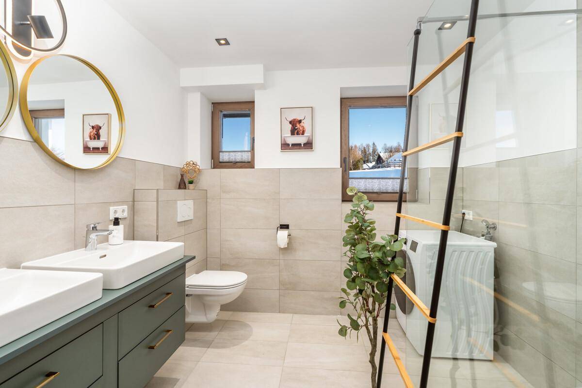 Modernes Badezimmer mit Doppelwaschbecken, Dusche und Waschmaschine.
