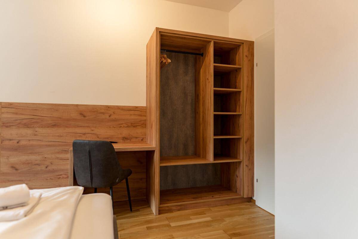 Schlafzimmer mit integriertem Kleiderschrank, Schreibtisch und Holzboden.