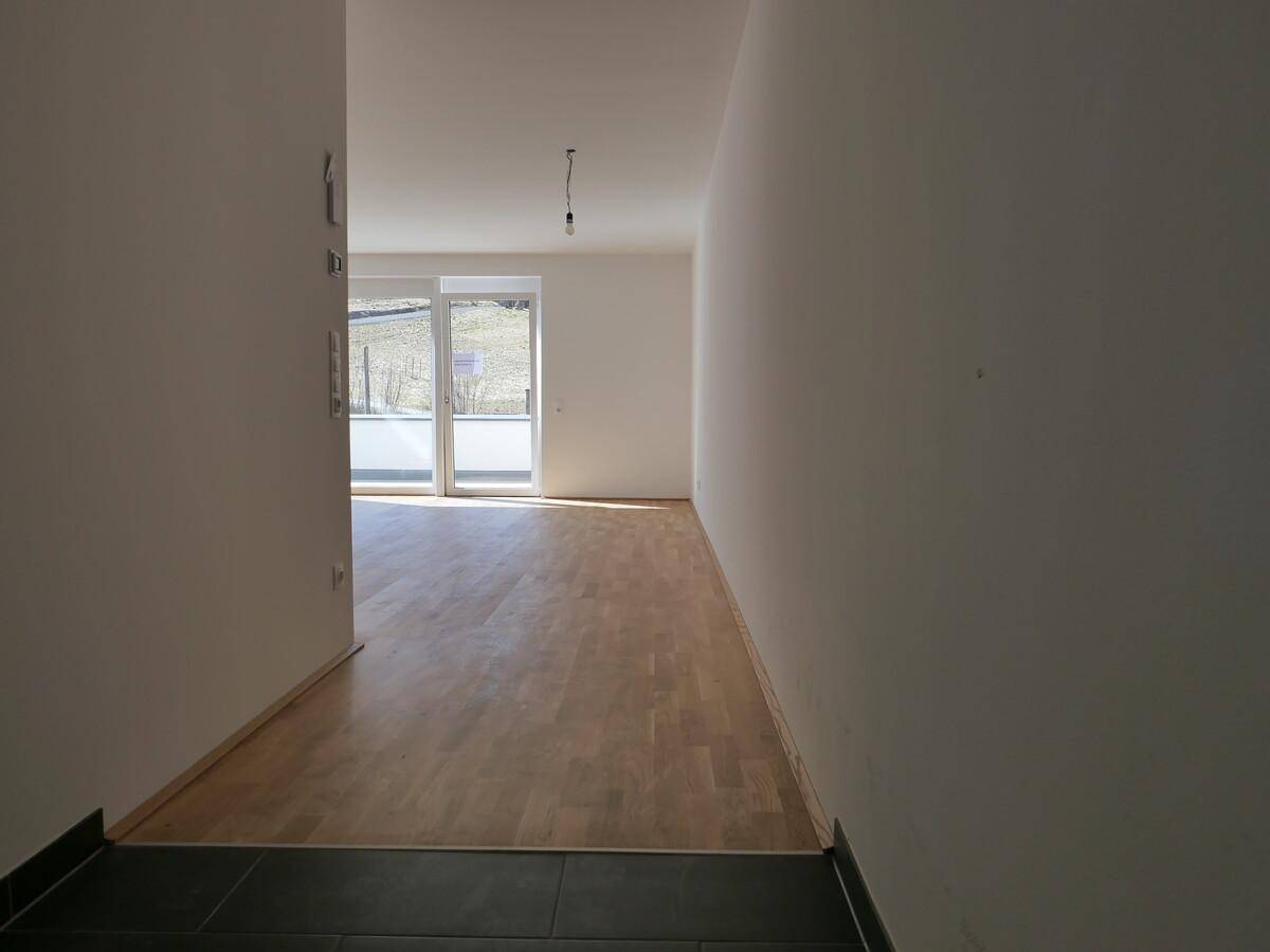 Heller Wohnbereich mit Holzboden und Zugang zu einem Balkon oder einer Terrasse.