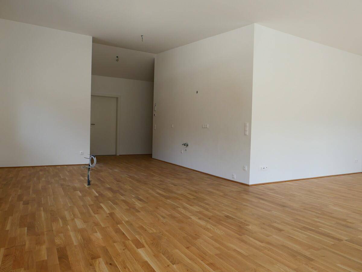 Geräumiger, leerer Raum mit hellem Holzboden und weißen Wänden, bereit zur Gestaltung.