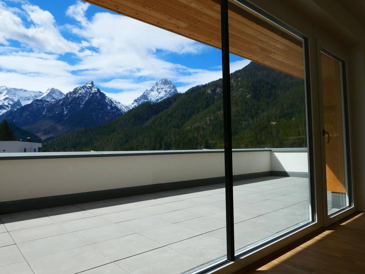 Geräumige Terrasse mit Fliesenboden und atemberaubendem Blick auf die schneebedeckten Berge.