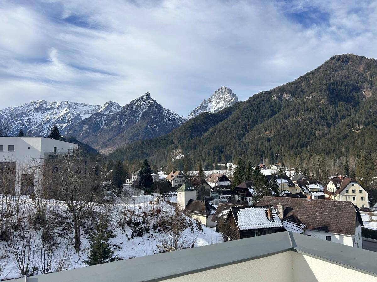 Panoramablick von einem Balkon auf ein verschneites Dorf und die majestätischen Berge im Hintergrund.