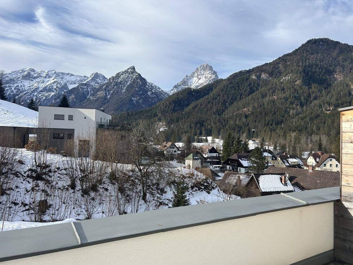 Weitblick von einer Terrasse auf ein verschneites Dorf und die umliegende Bergwelt mit moderner Architektur.