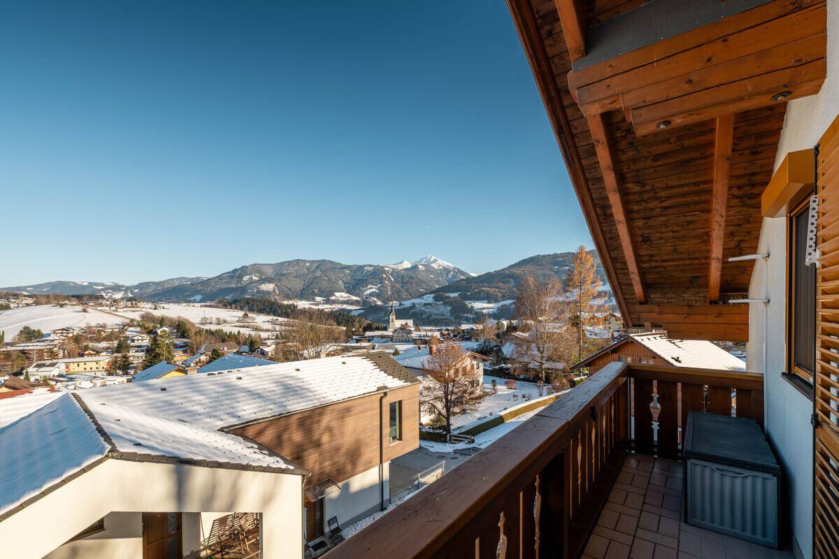 Geräumiger Balkon mit Holzelementen und weitem Blick über die verschneite Landschaft.