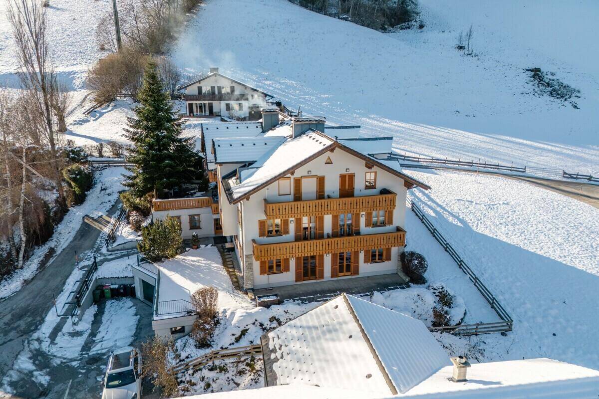 Luftaufnahme eines traditionellen Gebäudes in verschneiter Berglandschaft mit mehreren Balkonen.
