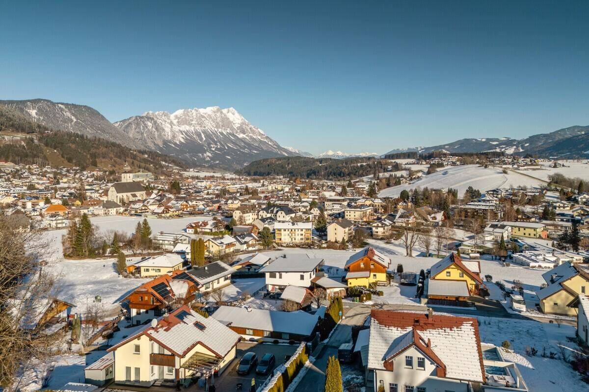Panoramablick auf eine verschneite Stadt in den Bergen unter blauem Himmel.
