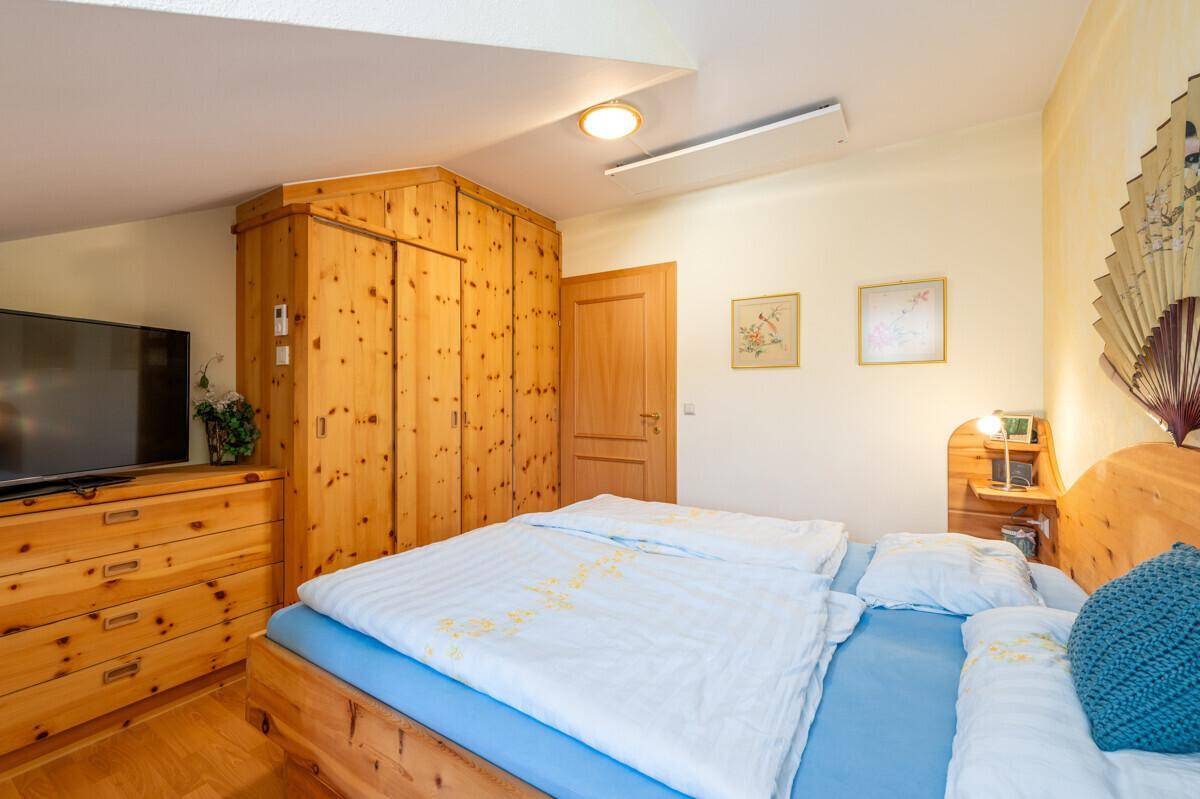 Schlafzimmer mit Holzbett, Holzschrank und Fernseher, gemütlich und funktional.