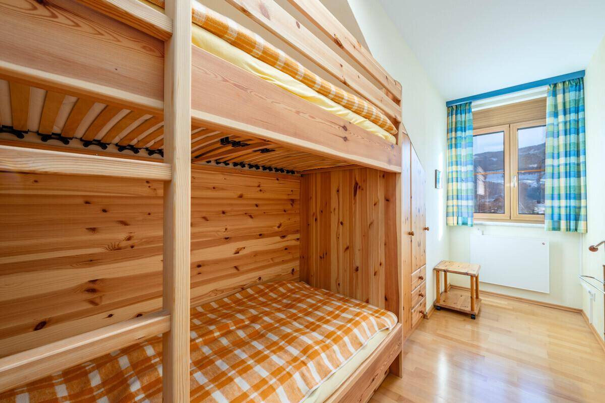 Kinderzimmer mit Etagenbett aus Holz und Fenster, hell und praktisch eingerichtet.