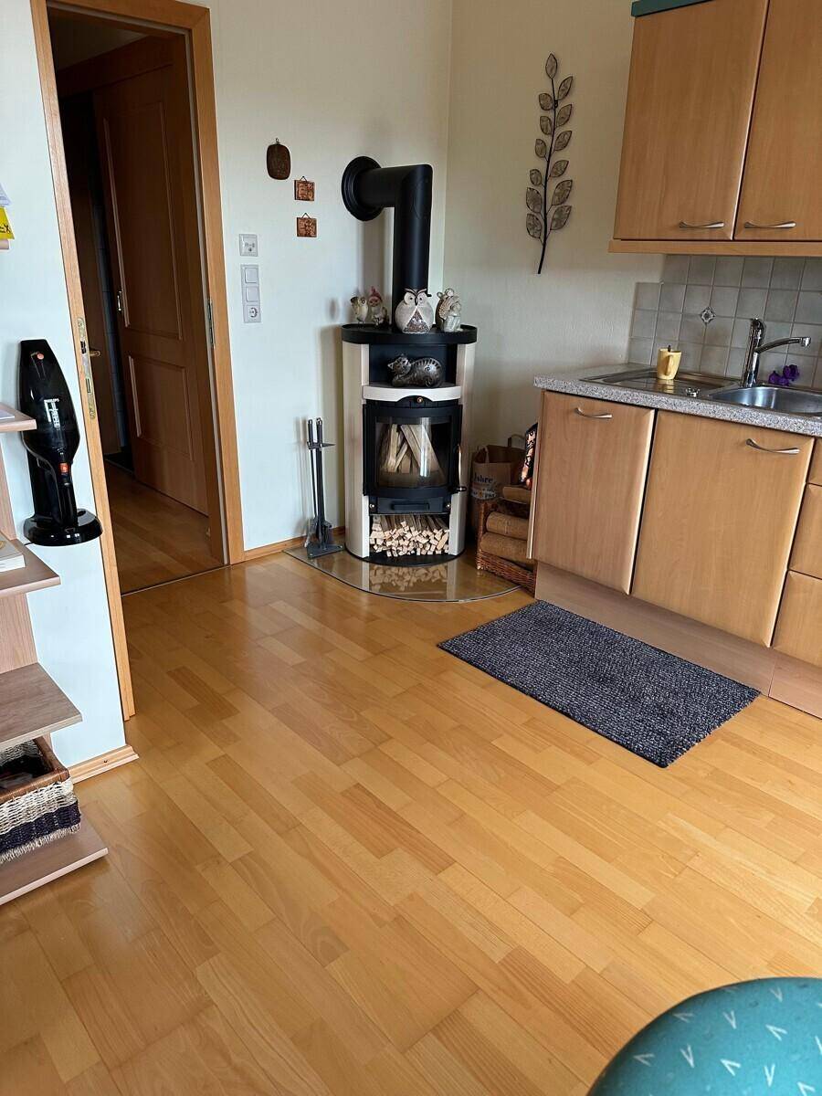 Detailansicht des Holzofens in der Küche mit Holzboden und traditionellen Elementen.