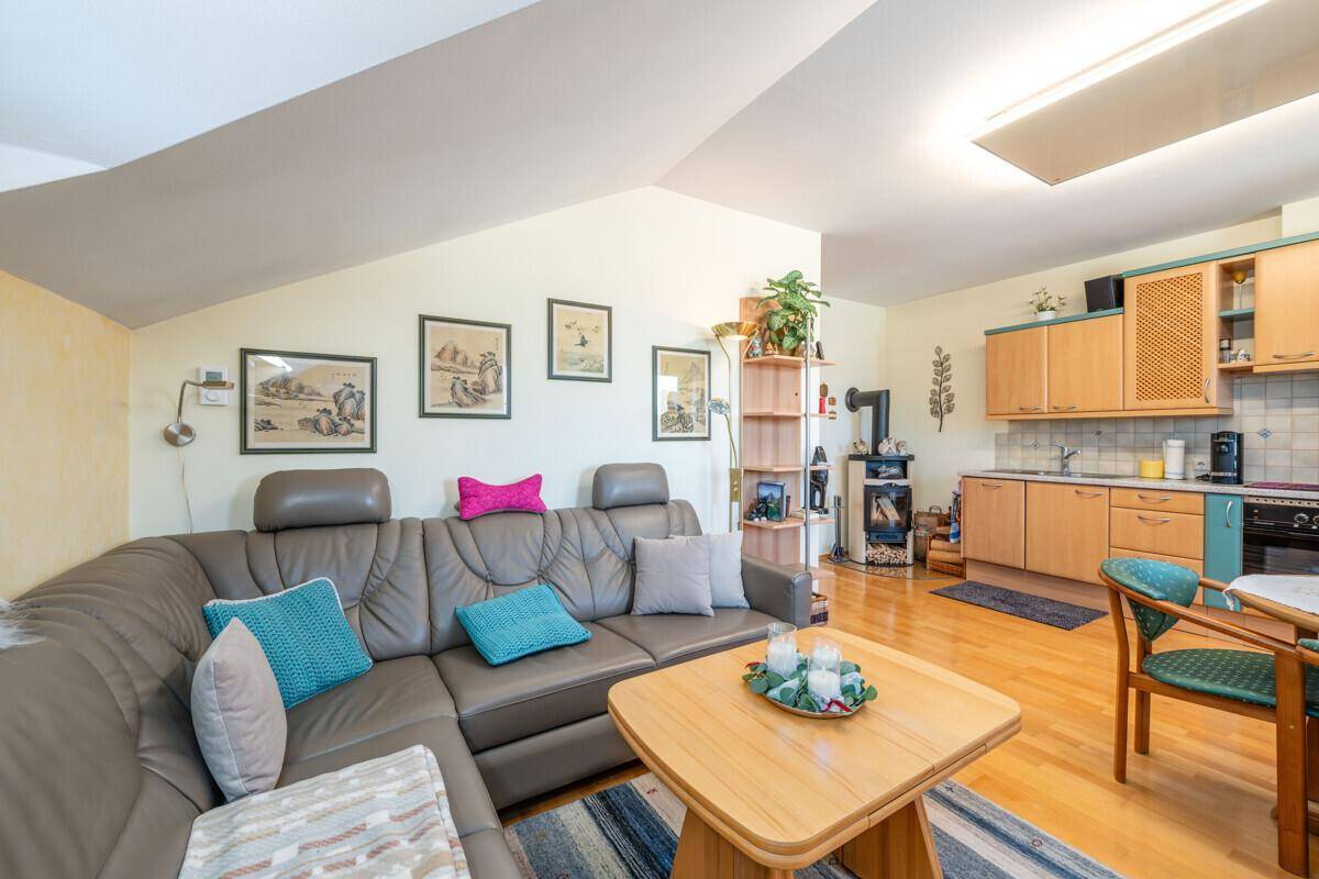 Offener Wohn- und Essbereich mit Küche, Ecksofa und Holzofen, ideal für gesellige Stunden.