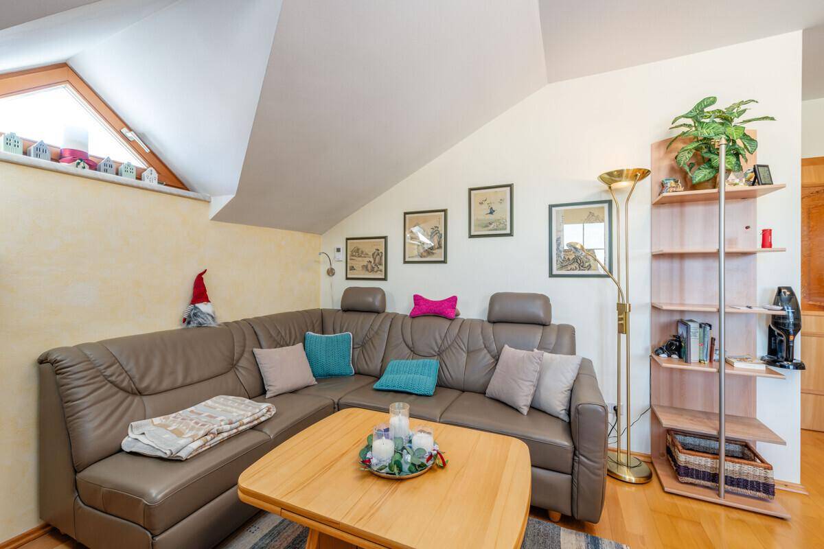 Gemütliches Wohnzimmer mit Ecksofa, Holztisch und Dachschrägen, hell und einladend.