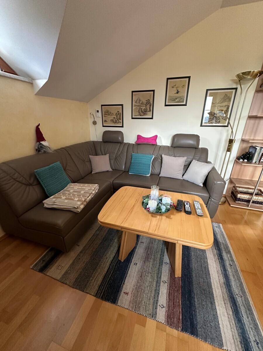 Gemütliches Wohnzimmer mit Ecksofa, Couchtisch und Teppich, unter Dachschrägen.