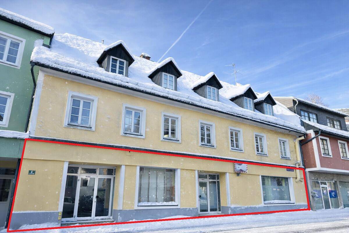 Historisches Gebäude mit gelber Fassade und roten Umrandungen, bedeckt mit Schnee im Winter.