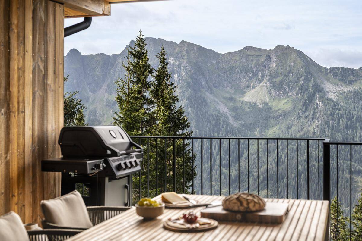 Großer Balkon mit Grillbereich, Esstisch und atemberaubendem Panoramablick auf die Berge.