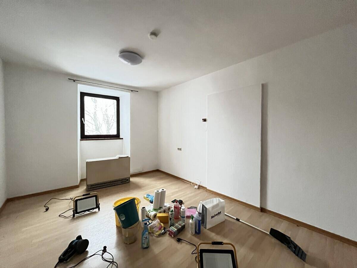 Leerer Raum mit Laminatboden und Reinigungsutensilien, bereit zur Übergabe oder Renovierung.