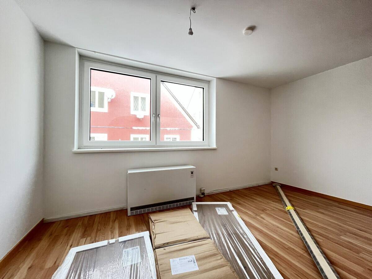 Heller Raum mit Fenster und Heizkörper, ausgestattet mit Laminatboden und natürlichem Licht.