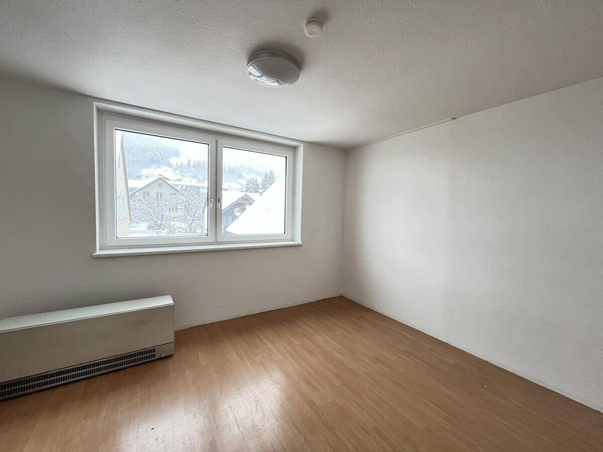 Helles Schlafzimmer mit Parkettboden und Blick auf die verschneite Landschaft.