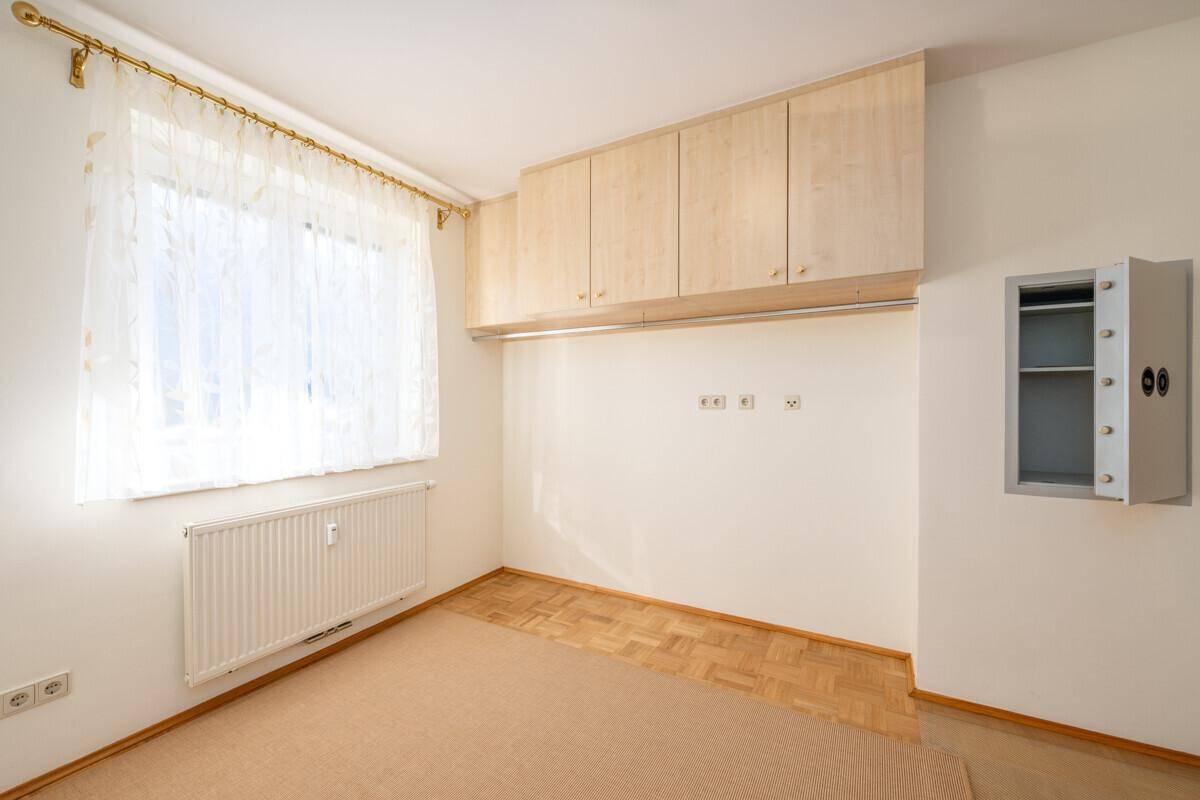 Schlafzimmer mit Parkettboden, Einbauschränken und einem Fenster für natürliches Licht.