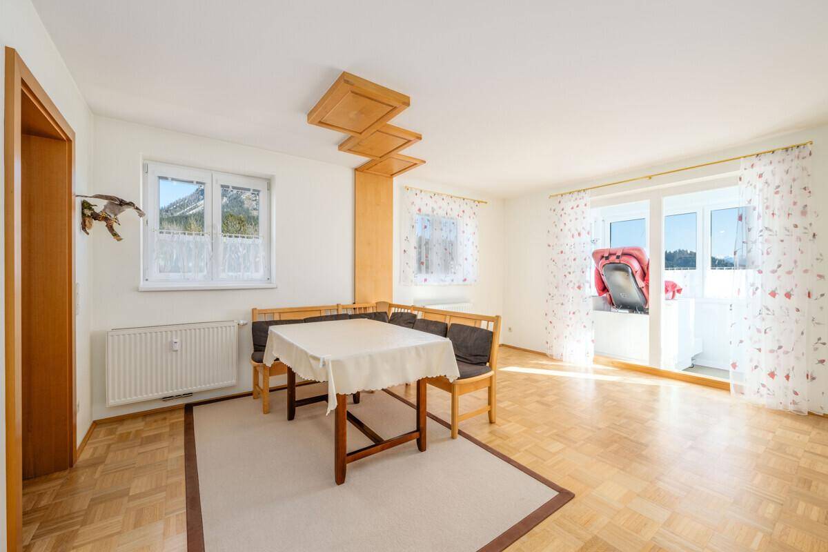 Geräumiger Wohn-Essbereich mit Parkettboden, Esstisch und Zugang zu einem sonnigen Balkon.