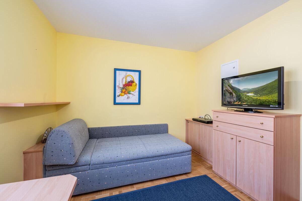 Gemütliches Zimmer mit Tagesbett, Fernseher und gelben Wänden, ideal als Gästezimmer.