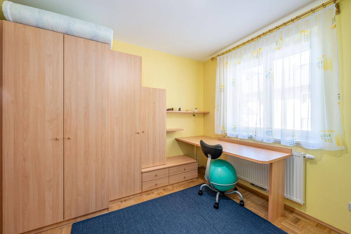 Kinderzimmer oder Arbeitszimmer mit gelben Wänden, Holzmöbeln und einem Schreibtisch.