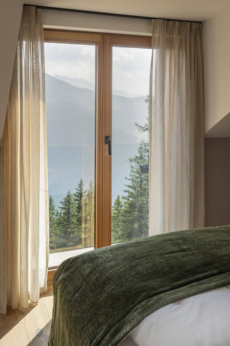 Großes Fenster im Schlafzimmer bietet einen weiten Blick auf die umliegende Berglandschaft.