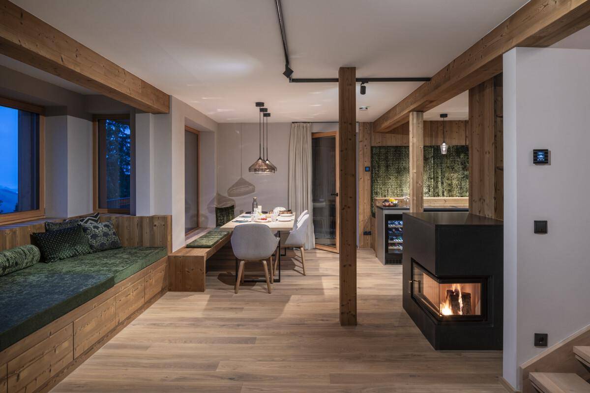 Geräumiger Wohn-Essbereich mit Kamin, Holzboden und integrierter Sitzbank mit Blick ins Grüne.