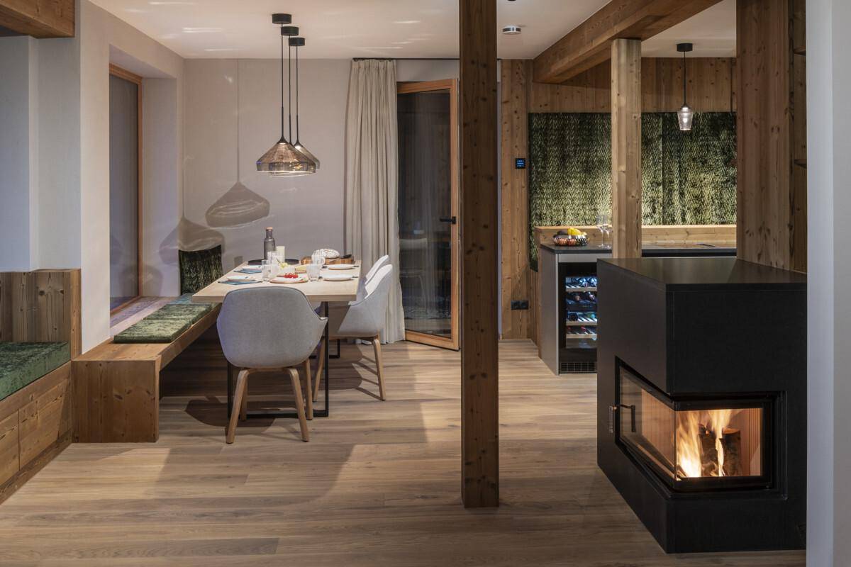 Gemütlicher Wohn-Essbereich mit Kamin, Holzboden und indirekter Beleuchtung für eine warme Atmosphäre.
