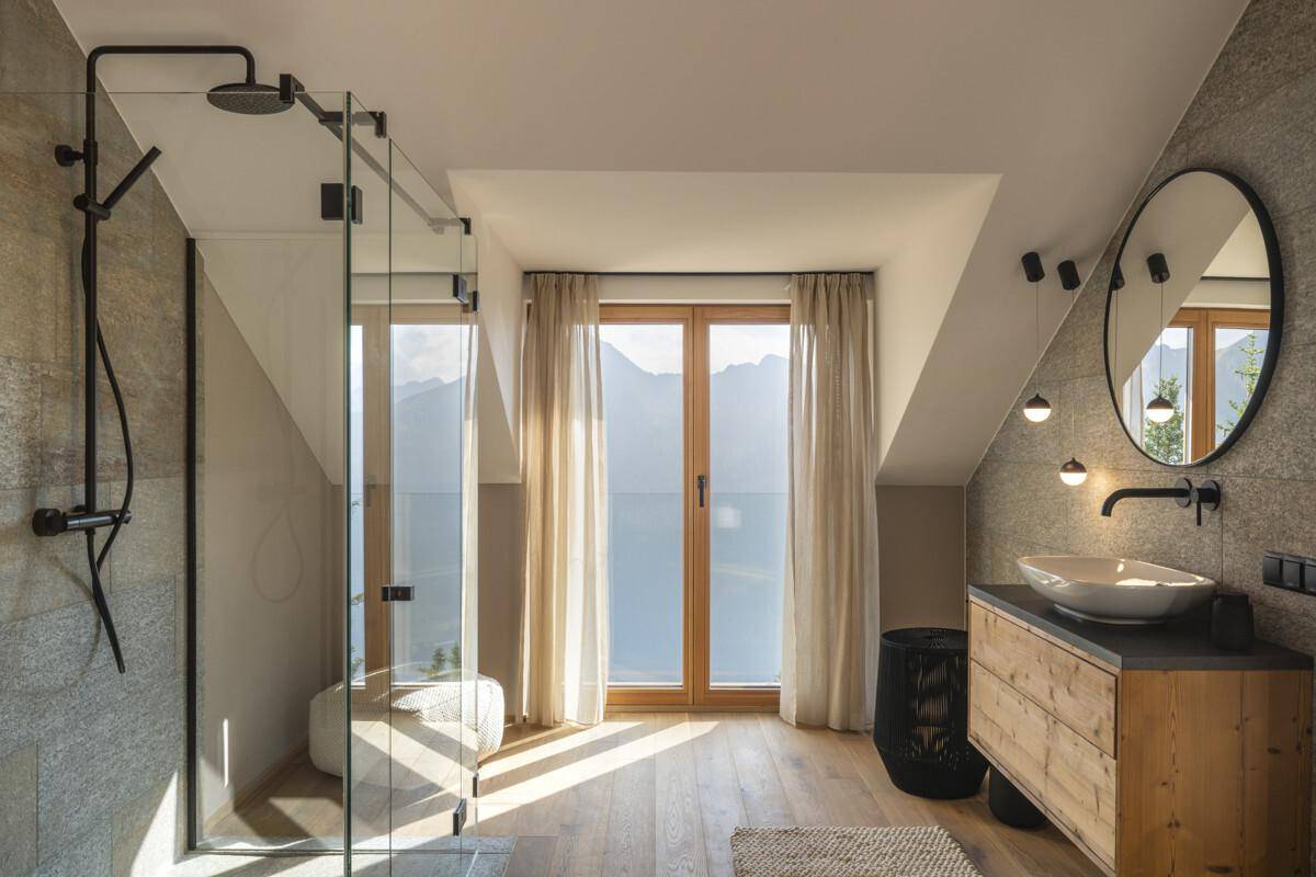 Modernes Badezimmer mit begehbarer Dusche, Waschtisch und großem Fenster mit Bergblick.